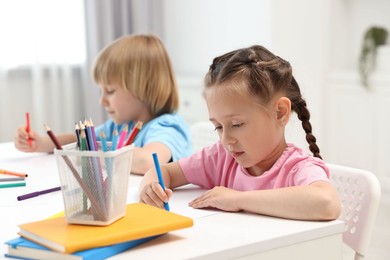 Photo of Cute little children drawing at table indoors