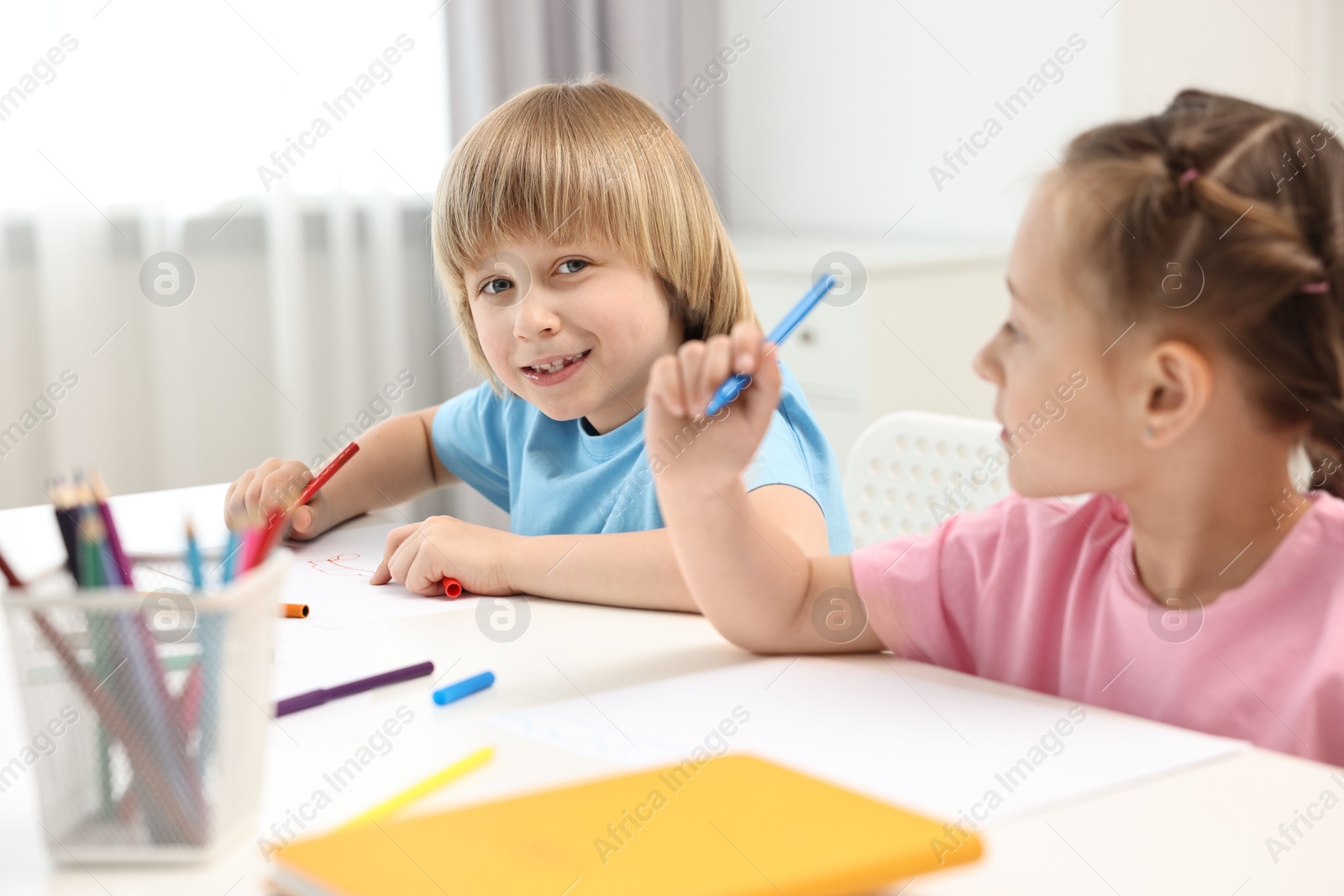 Photo of Cute little children drawing at table indoors