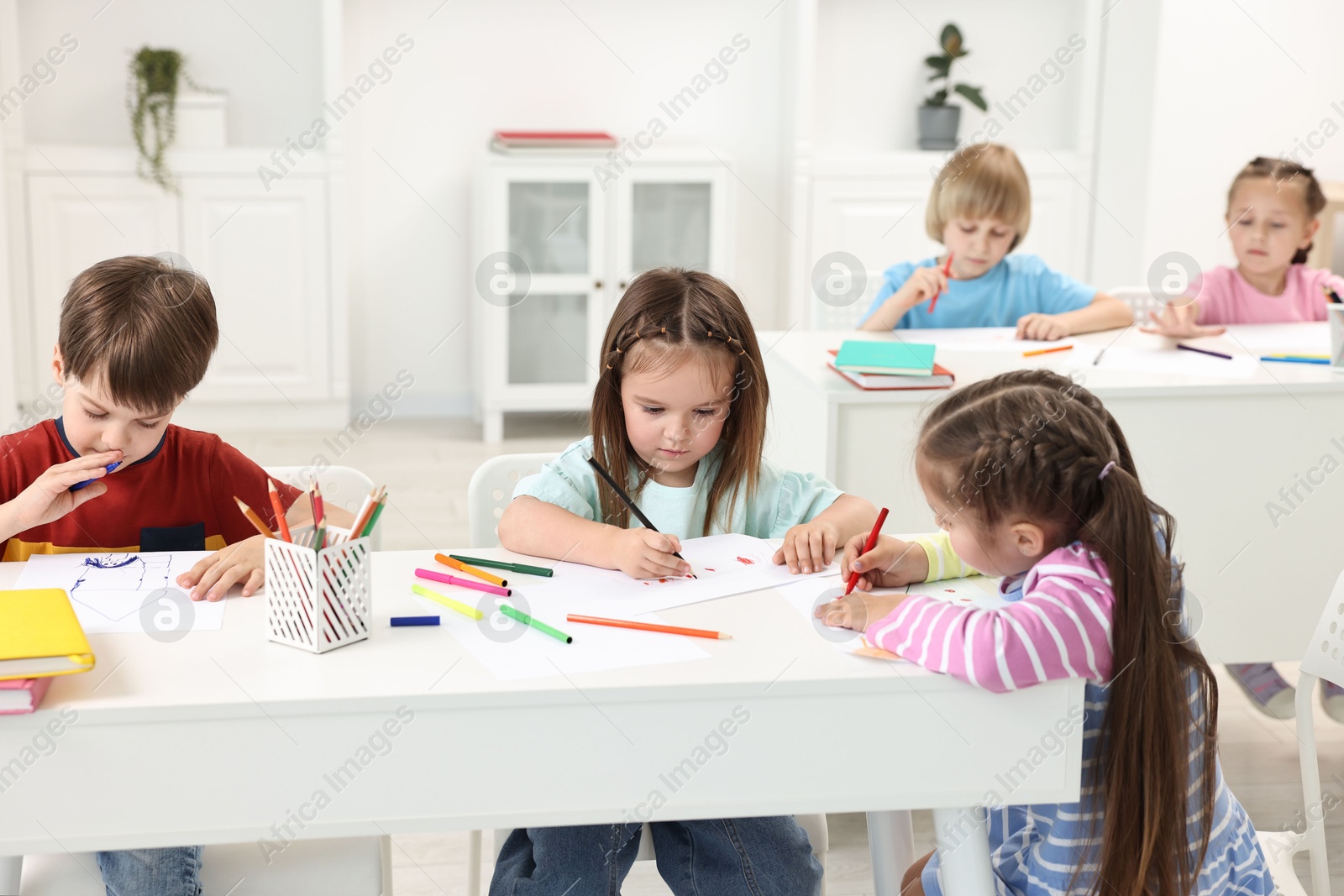 Photo of Group of children drawing at table indoors