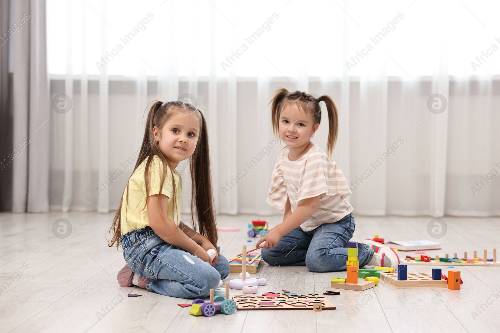 Photo of Cute little children playing together on floor indoors