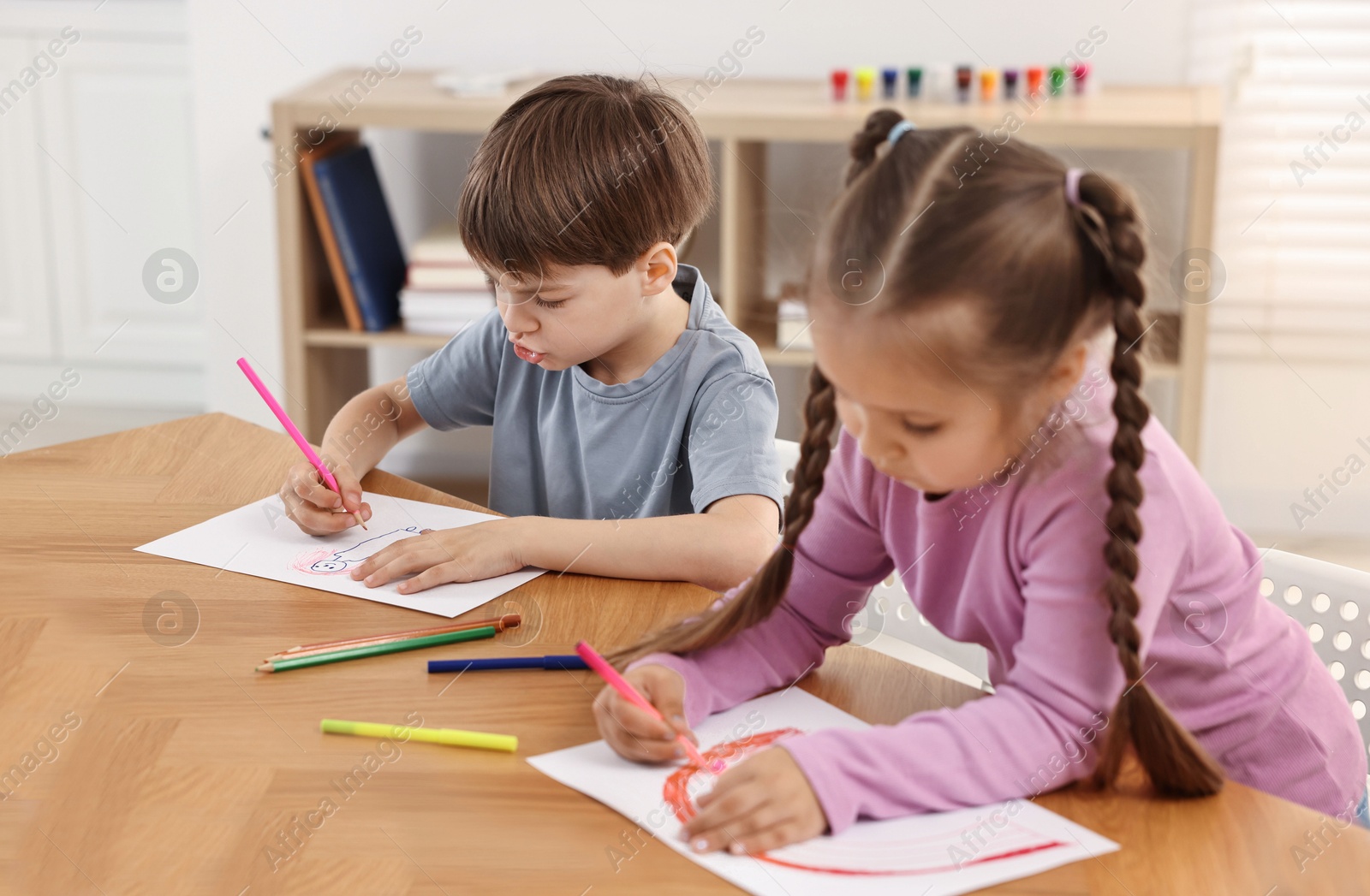 Photo of Cute little children drawing at wooden table indoors