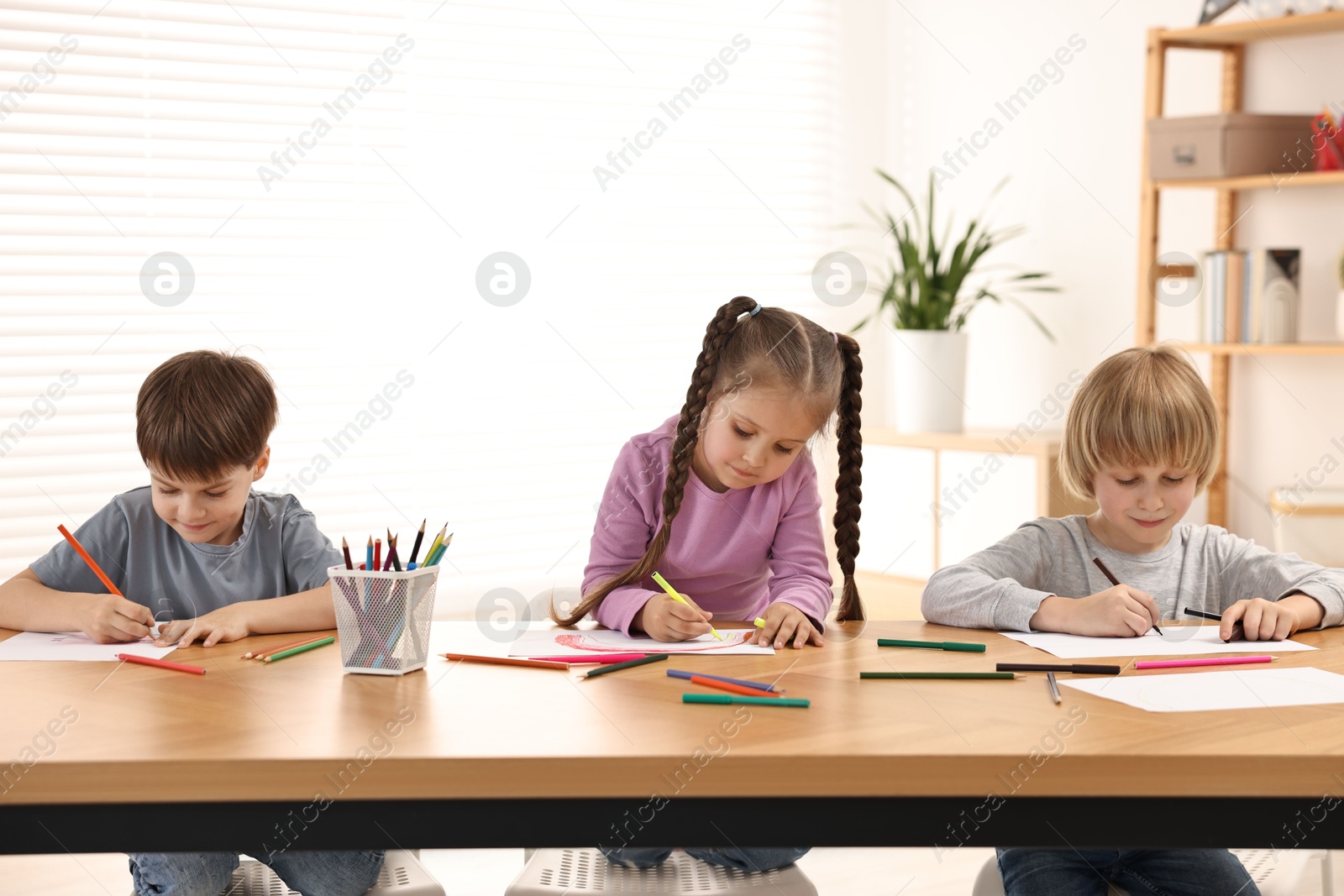 Photo of Cute little children drawing at wooden table indoors