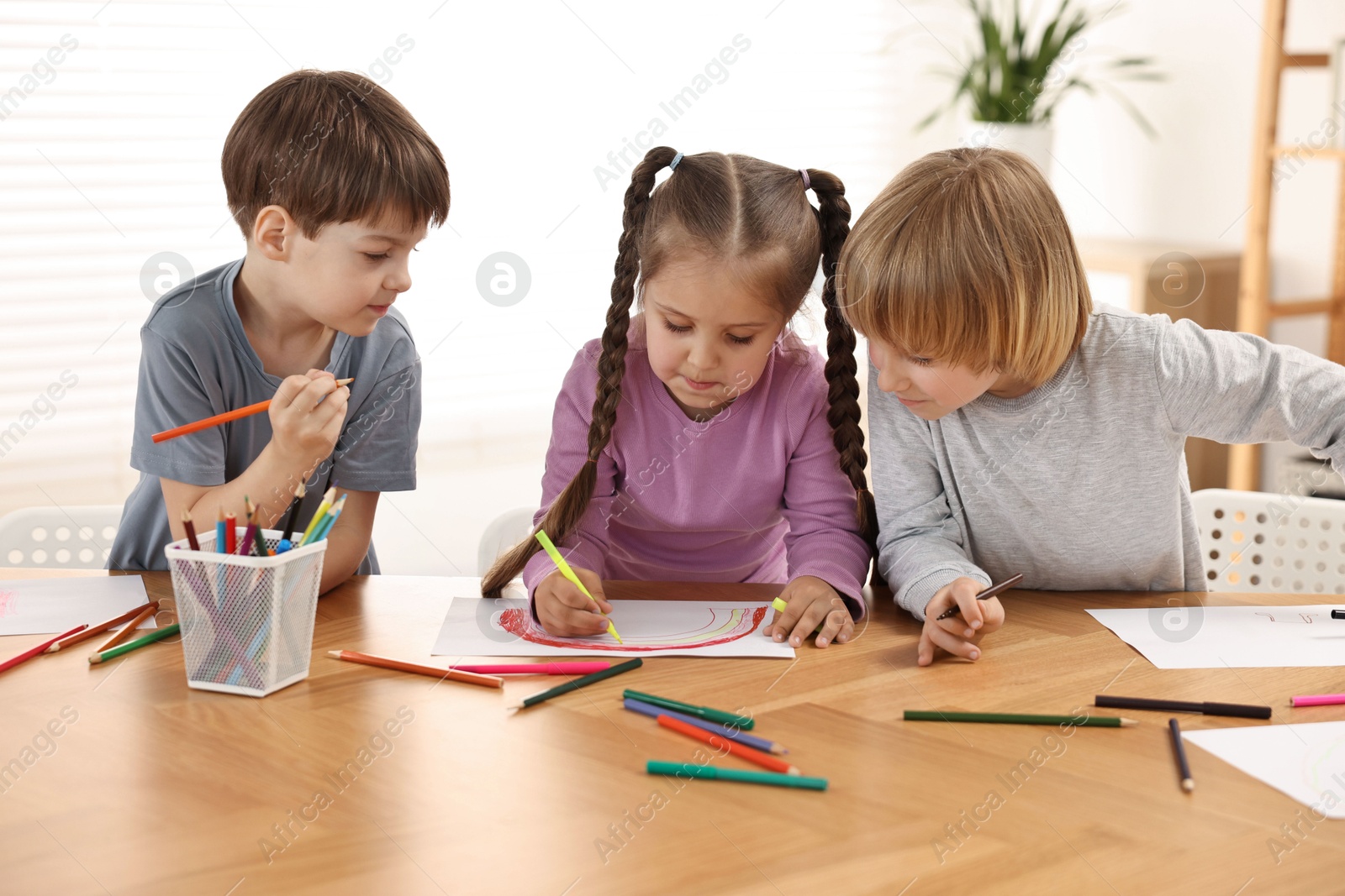 Photo of Cute little children drawing at wooden table indoors