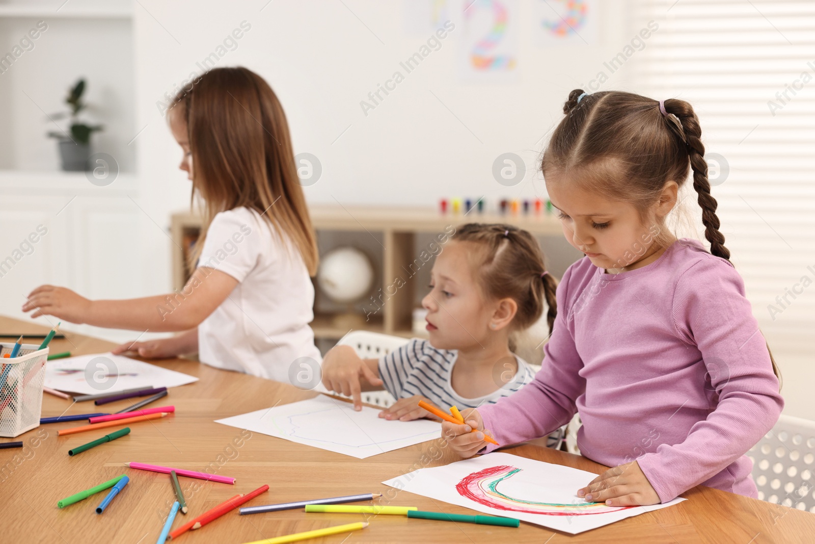 Photo of Cute little children drawing at wooden table indoors