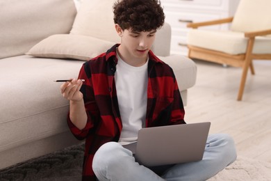 Photo of Teenager with pencil working on laptop at home. Remote job