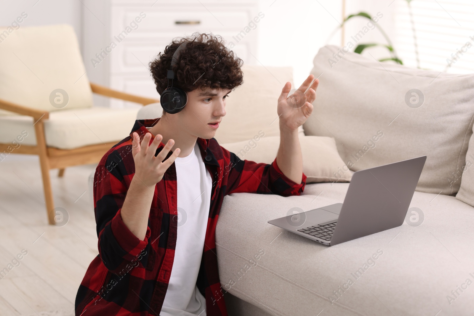 Photo of Teenager in headphones having video chat via laptop at home. Remote work