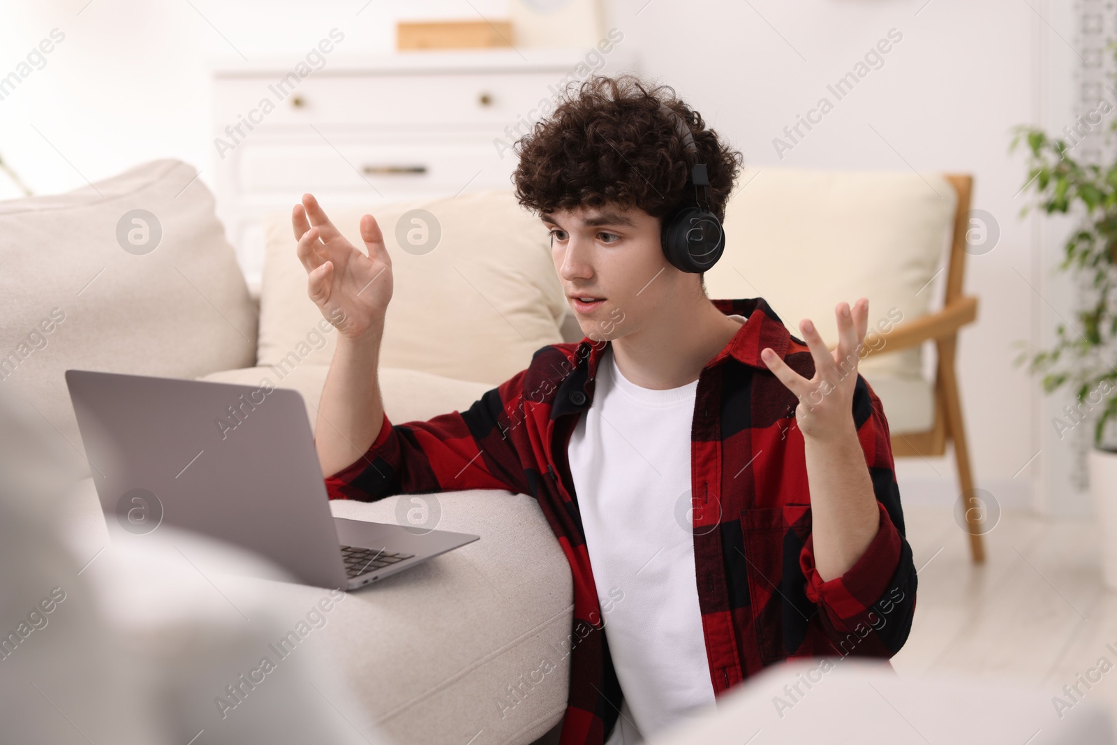 Photo of Teenager in headphones having video chat via laptop at home. Remote work