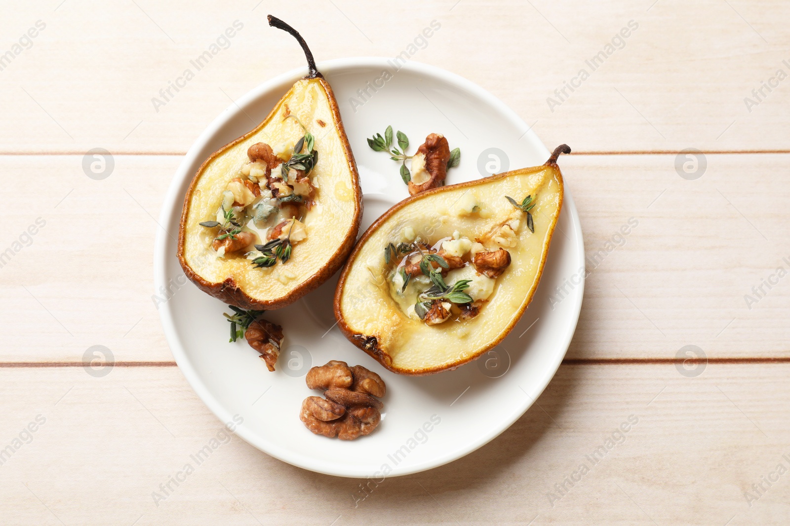 Photo of Tasty baked pears with nuts, blue cheese, thyme and honey on wooden table, top view