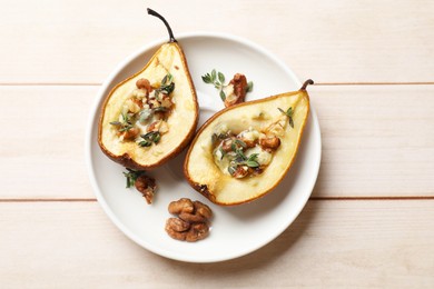 Photo of Tasty baked pears with nuts, blue cheese, thyme and honey on wooden table, top view