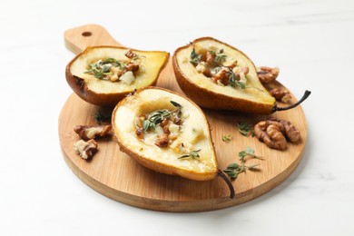 Photo of Tasty baked pears with nuts, blue cheese, thyme and honey dish on white table, closeup