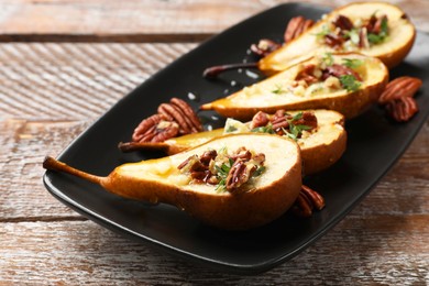 Photo of Tasty baked pears with nuts, blue cheese, thyme and honey on wooden table, closeup