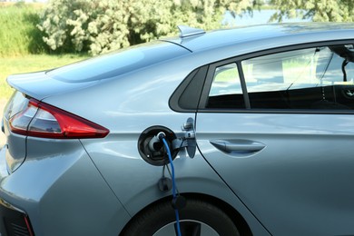 Photo of Charging modern electric car from station outdoors