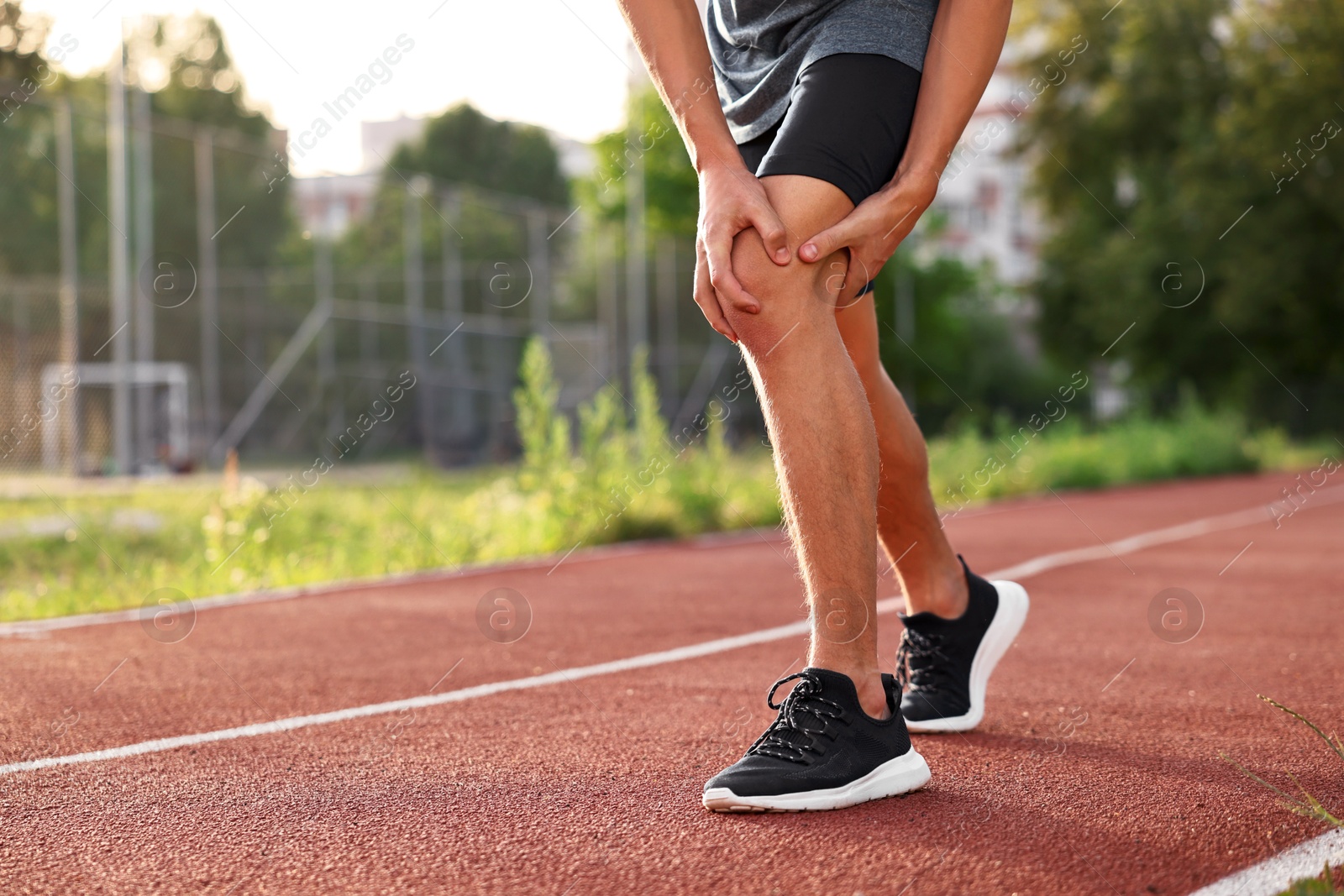 Photo of Sportsman with leg injury suffering from knee pain at stadium, closeup. Space for text