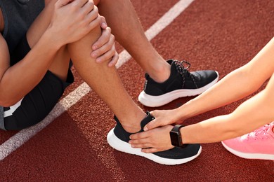 Sports injury. Woman helping man with leg pain at stadium, closeup