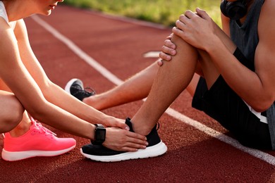 Sports injury. Woman helping man with leg pain at stadium, closeup