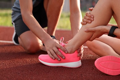 Sports injury. Man helping woman with leg pain at stadium, closeup