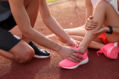 Sports injury. Man helping woman with leg pain at stadium, closeup