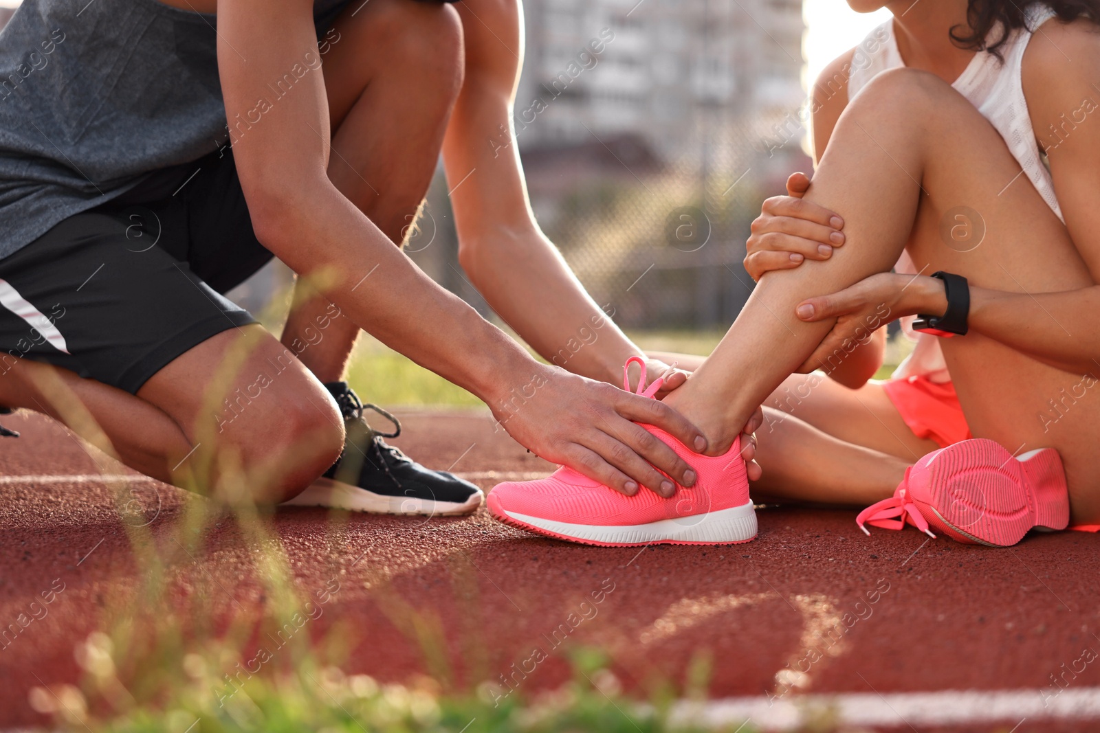 Photo of Sports injury. Man helping woman with leg pain at stadium, closeup