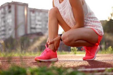 Photo of Sportswoman with injured leg at stadium, closeup