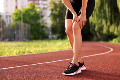 Sportswoman with leg injury suffering from knee pain at stadium, closeup. Space for text