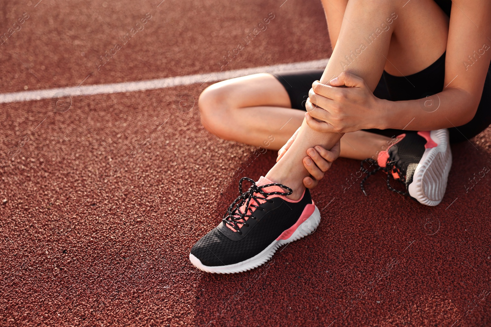 Photo of Sportswoman with leg injury at stadium, closeup. Space for text