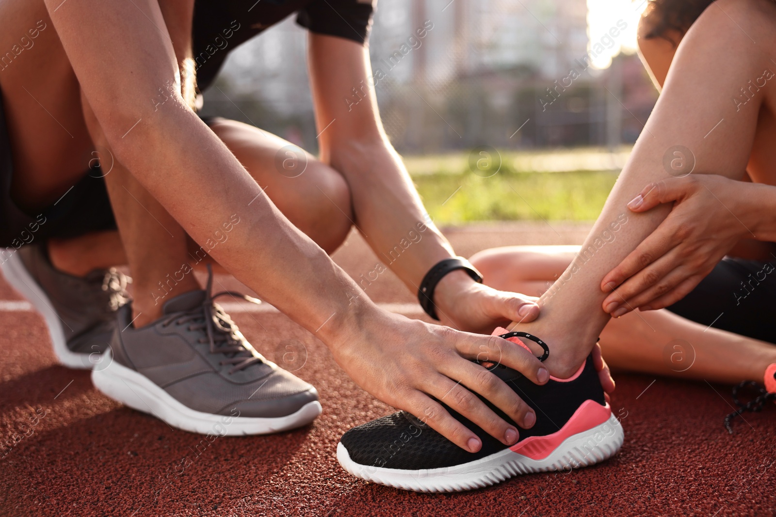 Photo of Sports injury. Man helping woman with leg pain at stadium, closeup