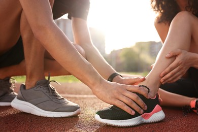 Sports injury. Man helping woman with leg pain at stadium, closeup