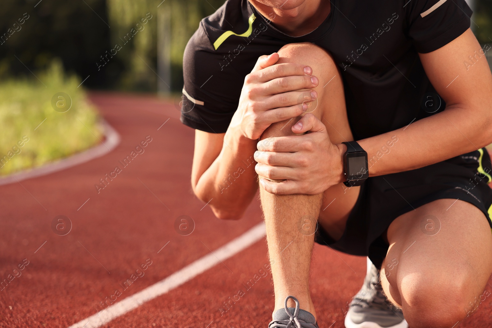 Photo of Sportsman with leg injury suffering from knee pain at stadium, closeup. Space for text