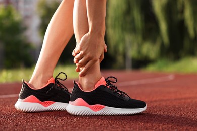 Sportswoman with injured leg at stadium, closeup