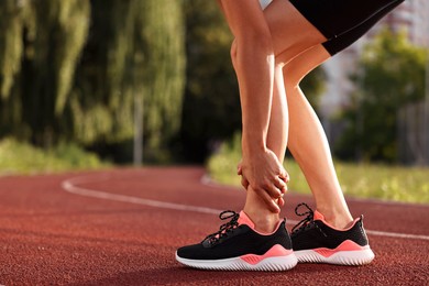 Photo of Sportswoman with leg injury at stadium, closeup. Space for text