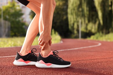 Sportswoman with leg injury at stadium, closeup. Space for text