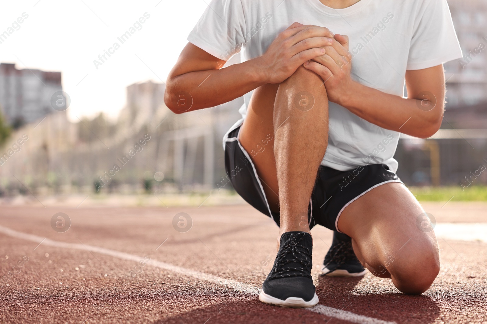 Photo of Sportsman with leg injury suffering from knee pain at stadium, closeup. Space for text