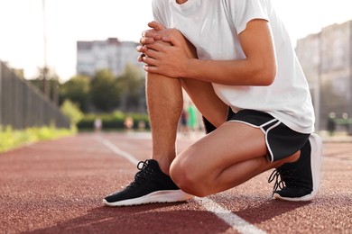 Photo of Sportsman with leg injury suffering from knee pain at stadium, closeup. Space for text