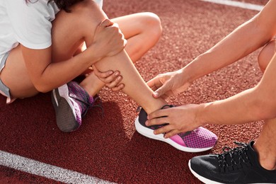 Sports injury. Man helping woman with leg pain at stadium, closeup