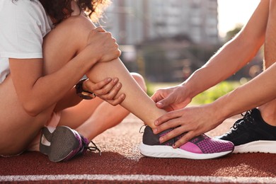 Sports injury. Man helping woman with leg pain at stadium, closeup