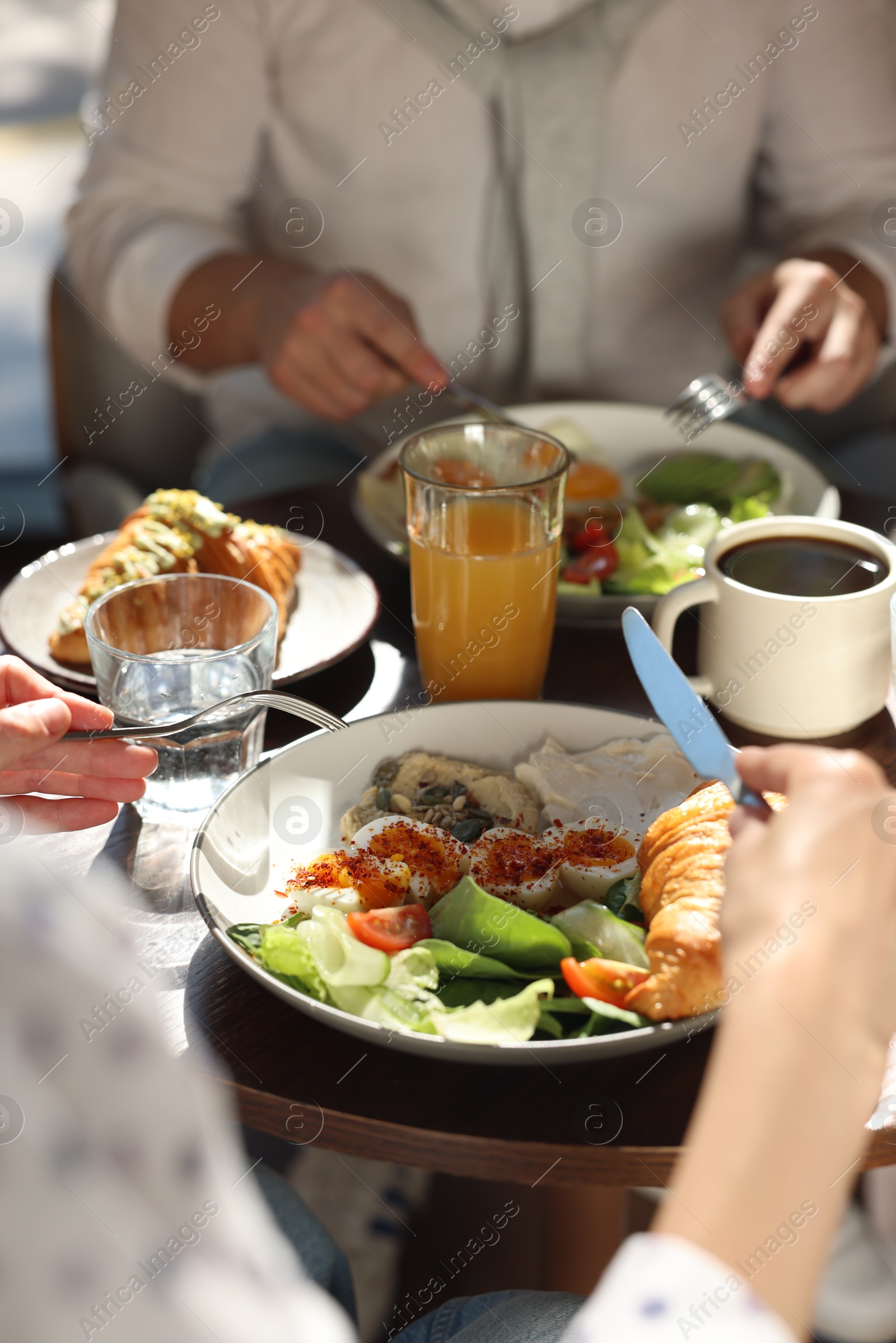 Photo of Couple having tasty breakfast at wooden table in cafe, closeup