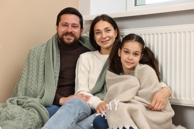 Photo of Happy family near heating radiator at home