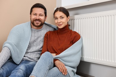 Photo of Happy couple near heating radiator at home