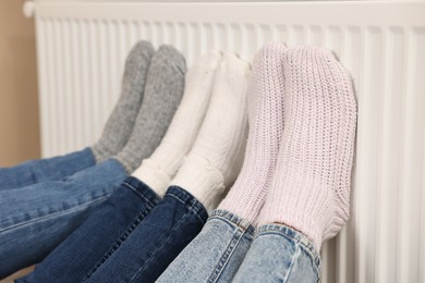 Family warming feet near heating radiator at home, closeup