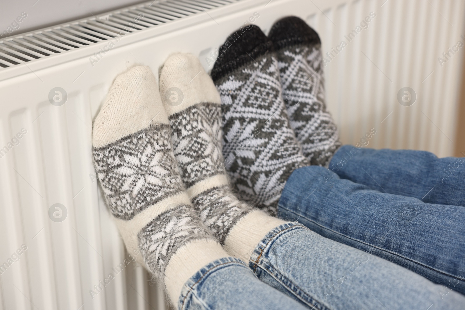 Photo of Couple warming feet near heating radiator at home, closeup