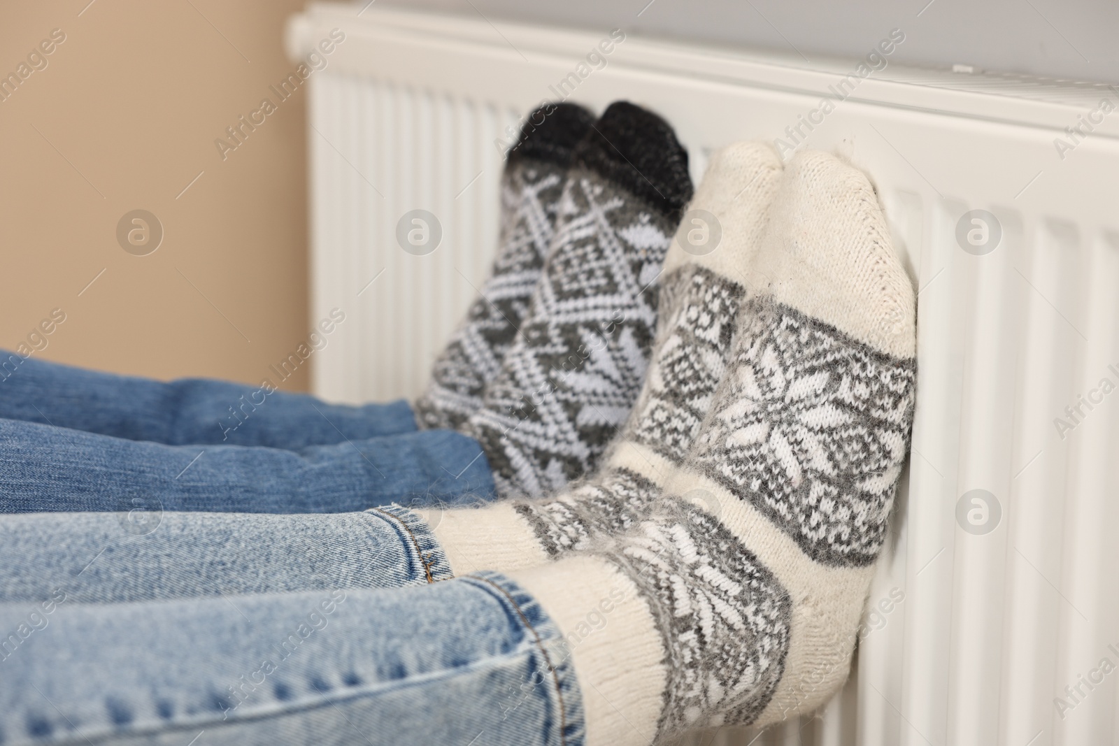 Photo of Couple warming feet near heating radiator at home, closeup