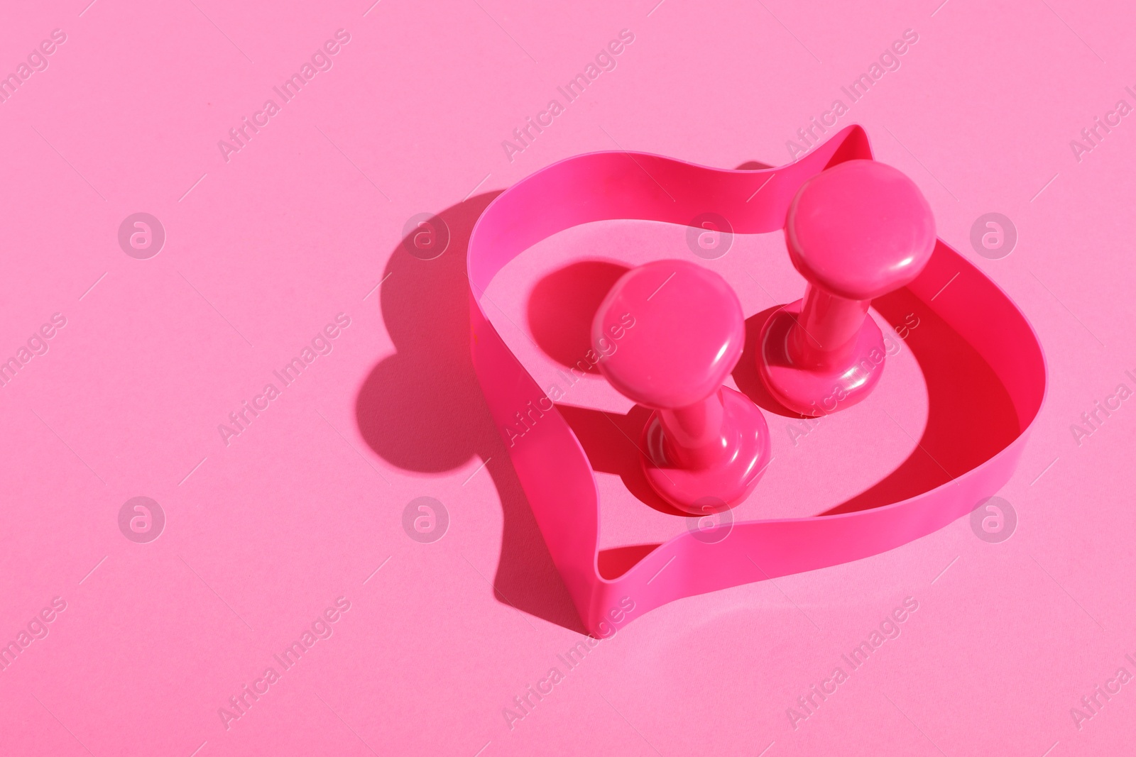 Photo of Dumbbells and fitness elastic band on pink background. Space for text