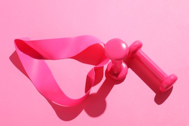 Photo of Dumbbells and fitness elastic band on pink background, above view