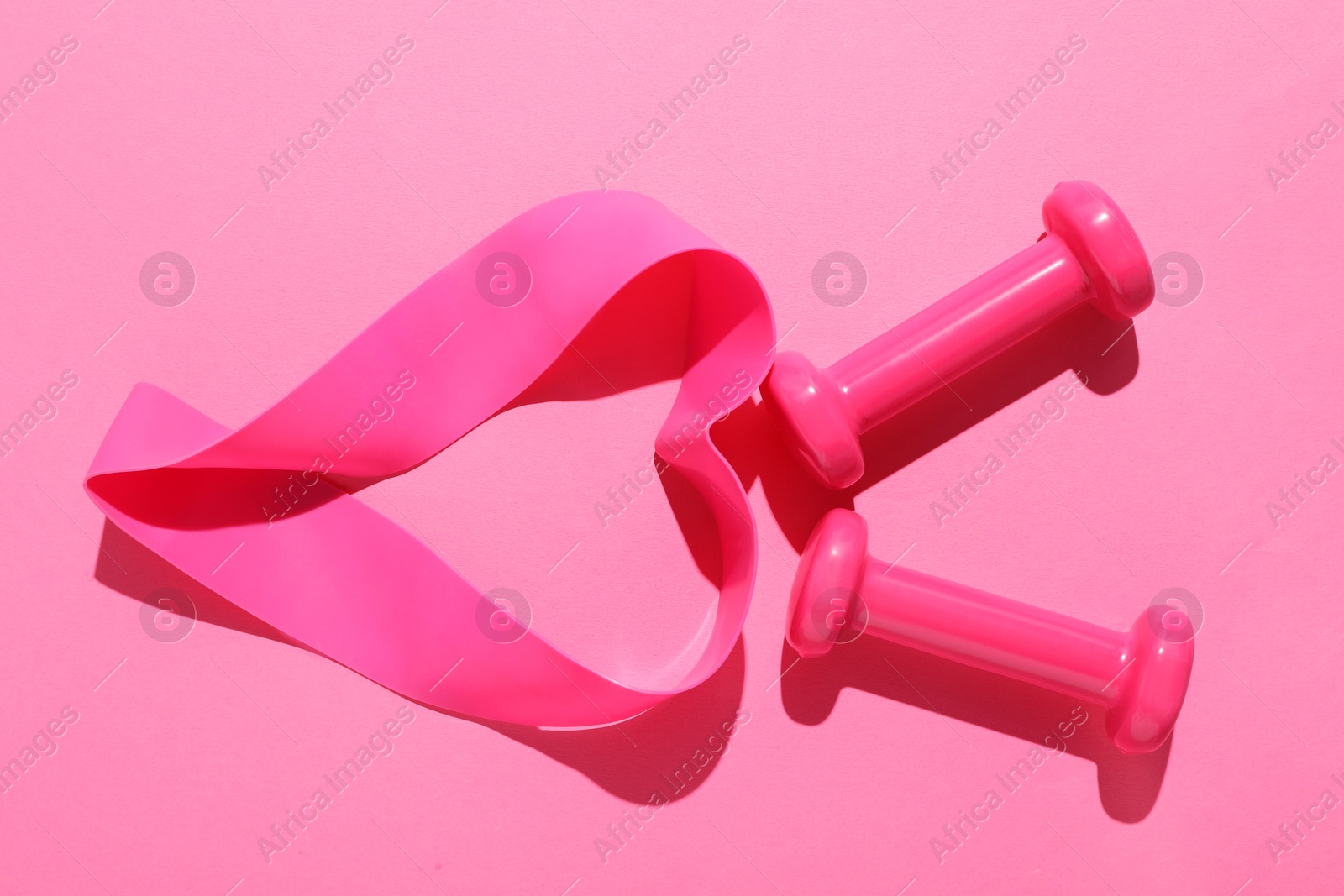 Photo of Dumbbells and fitness elastic band on pink background, flat lay