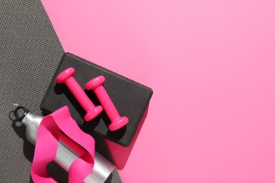 Photo of Dumbbells and other sports equipment on pink background, flat lay. Space for text