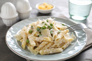 Photo of Delicious pasta with green peas, cheese and creamy sauce on grey table, closeup