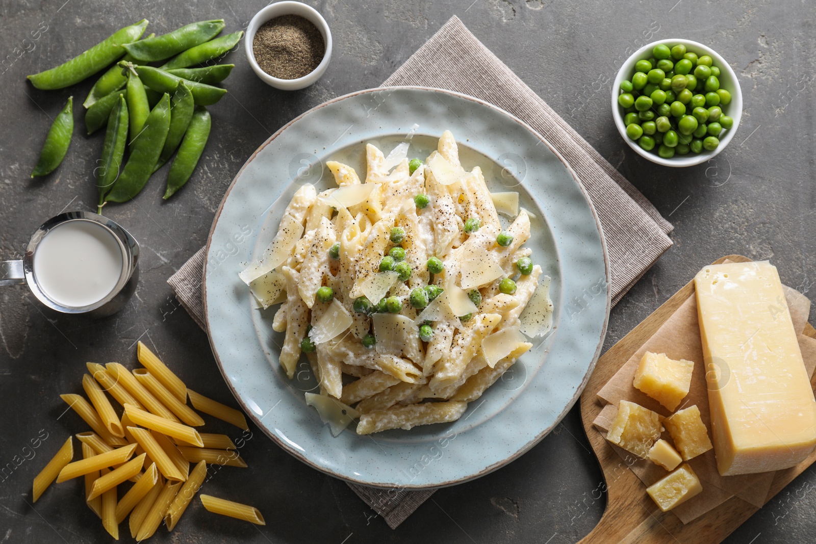 Photo of Delicious pasta with green peas, cheese, creamy sauce and ground pepper on grey table, top view