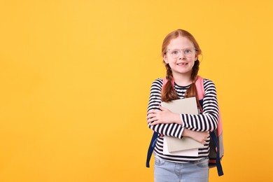 Photo of Smiling girl with book on yellow background. Space for text