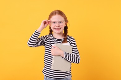 Photo of Smiling girl with books on yellow background