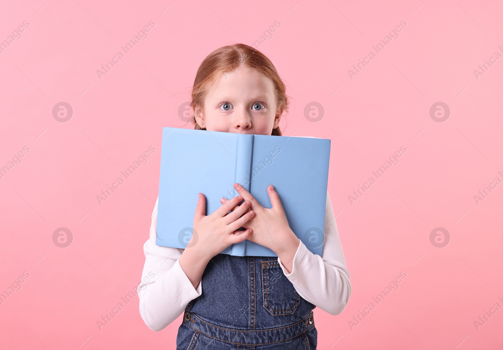 Photo of Cute little girl with books on pink background